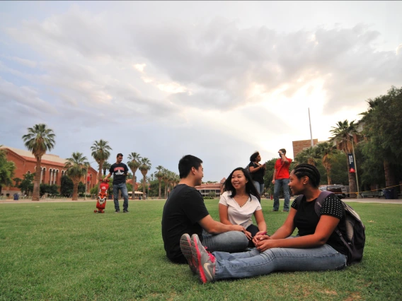 Three people sitting in the UA Mall talking happily.