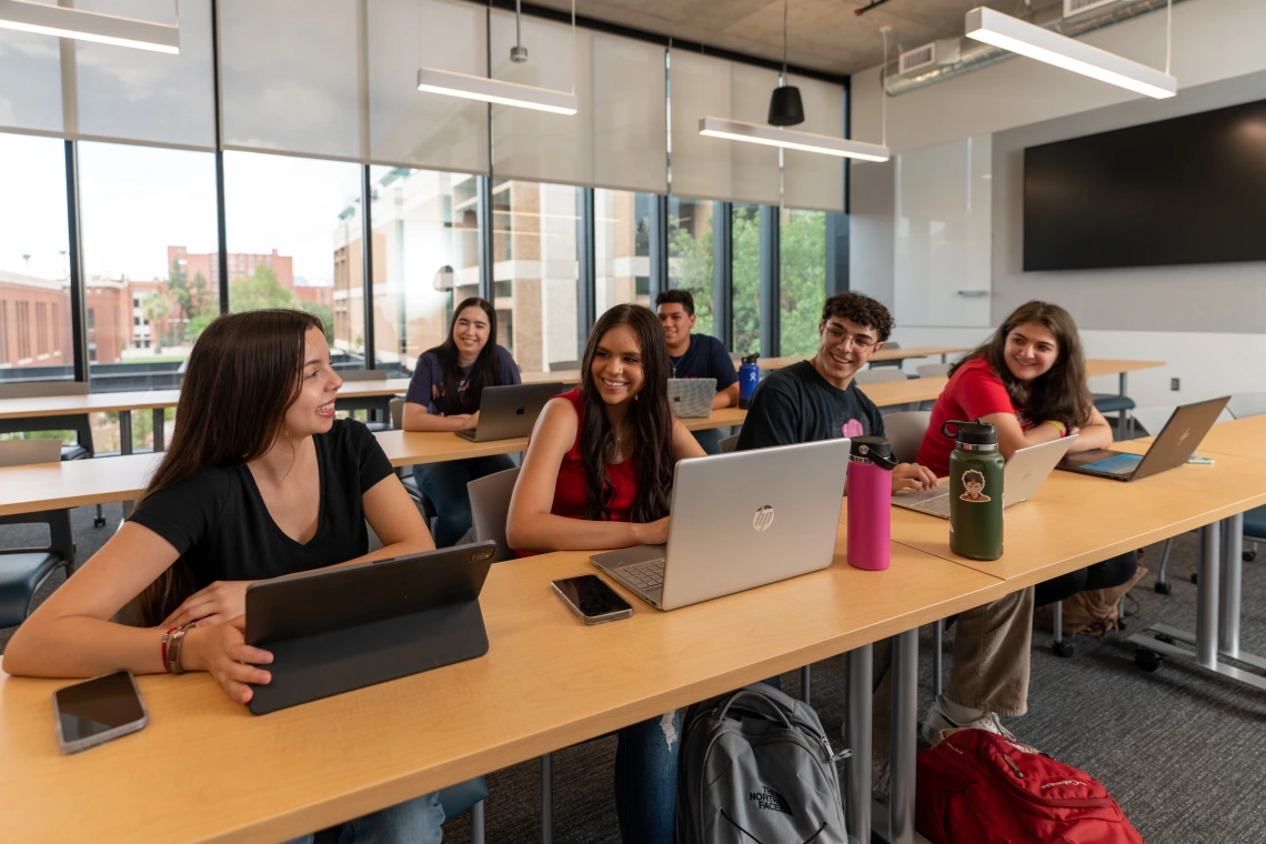 A group of four students sitting side by side at a table. 